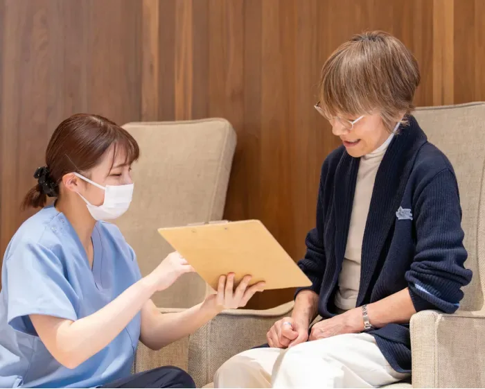 椅子に座る患者様と書類を見ながら話すスタッフ