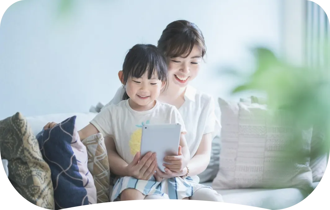 ソファでタブレットを一緒に見る女性と子ども