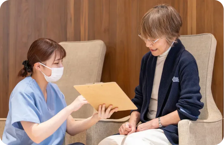 椅子に座る患者様と書類を見ながら話すスタッフ